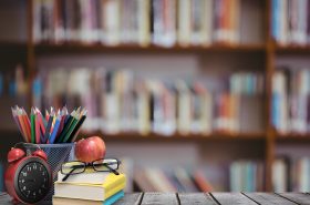 digital composite of School materials and apple with library background